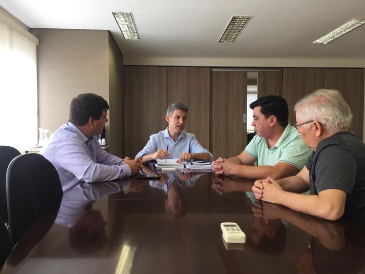 Foto do prefeito de Tijucas do Sul, Antônio César Matucheski e do presidente da Comec Gilson SAntos conversando em uma mesa no gabinete do presidente da comec