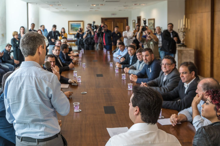 GIlson Santos em pé falando para grupo de pessoas na sala de reunião do palácio do Iguaçu